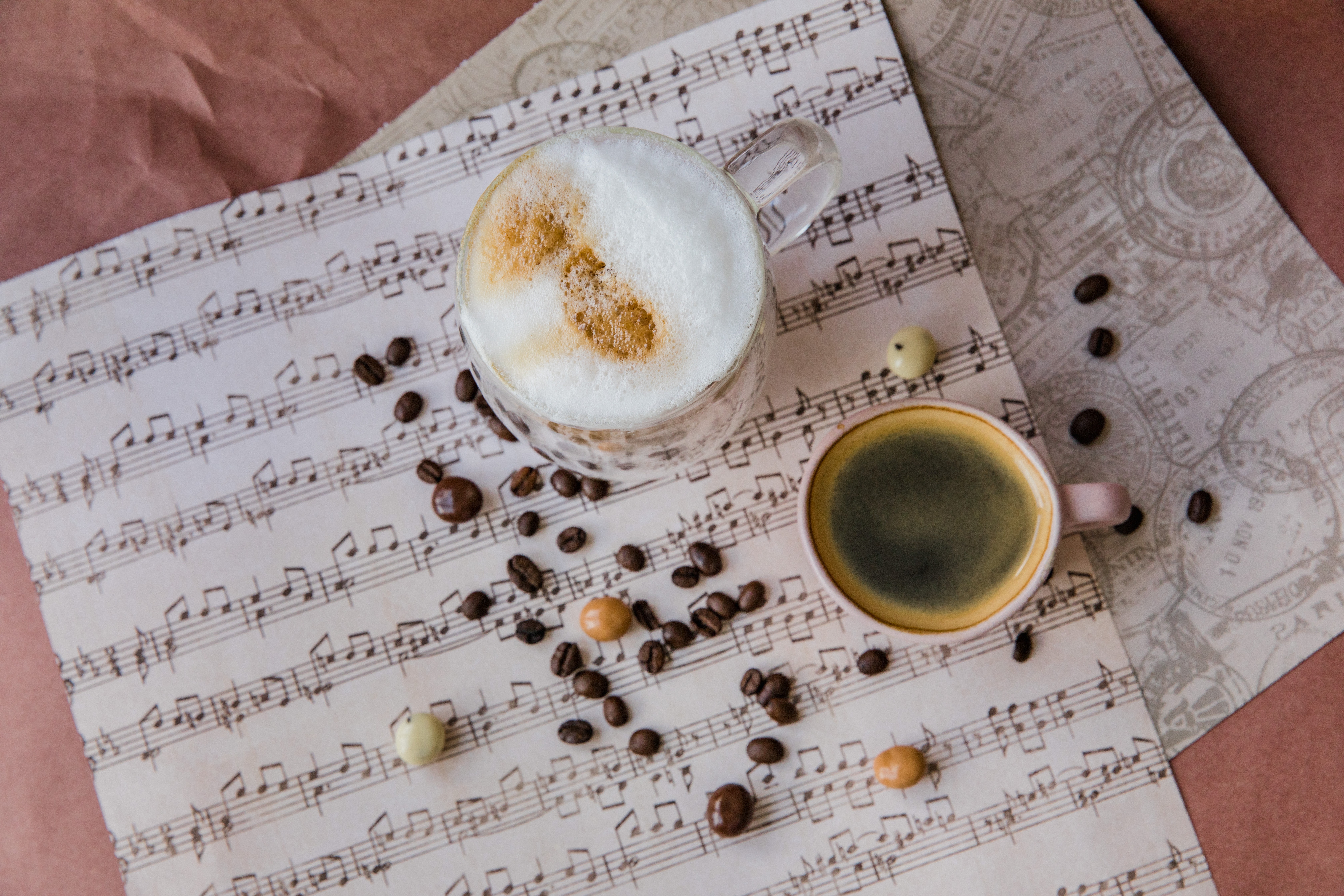mug of coffee on sheet music with coffee beans scattered around
