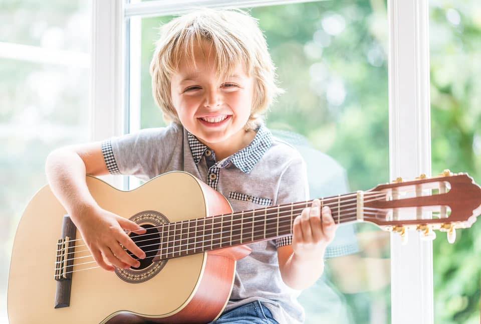 boy smiling holding guitar